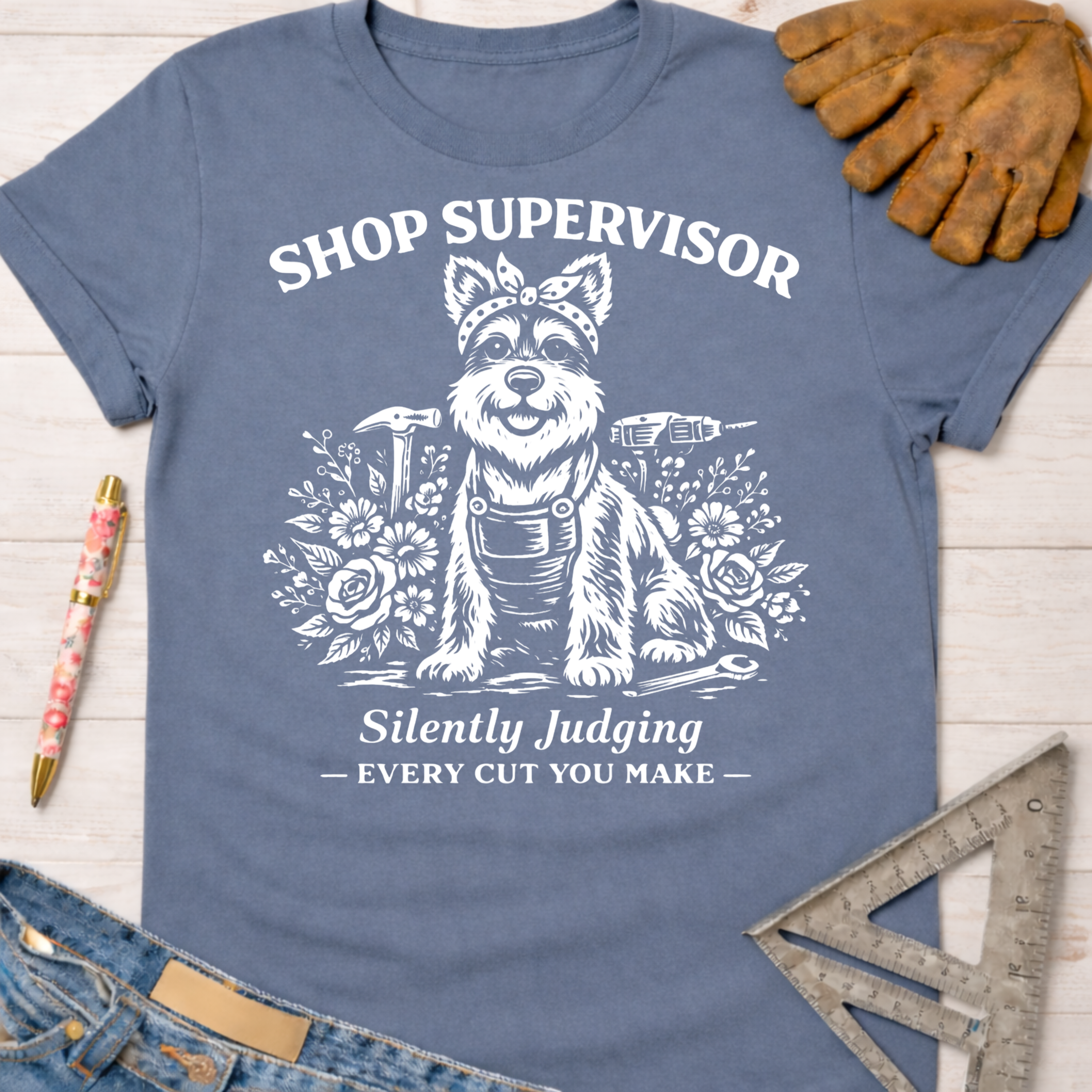 Women's funny woodworking graphic tee shirt for female woodworkers, makers, and DIY builders — Sawdust & Ponytails. Blue cotton tee with white "Shop Supervisor Silently Judging" text and a dog in overalls surrounded by tools and flowers.