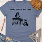 Women's funny woodworking graphic tee shirt for female woodworkers, makers, and DIY builders — Sawdust & Ponytails. Blue cotton tee with "SHOP TIME = ME TIME" text and a graphic of a woman sawing wood with her dog.