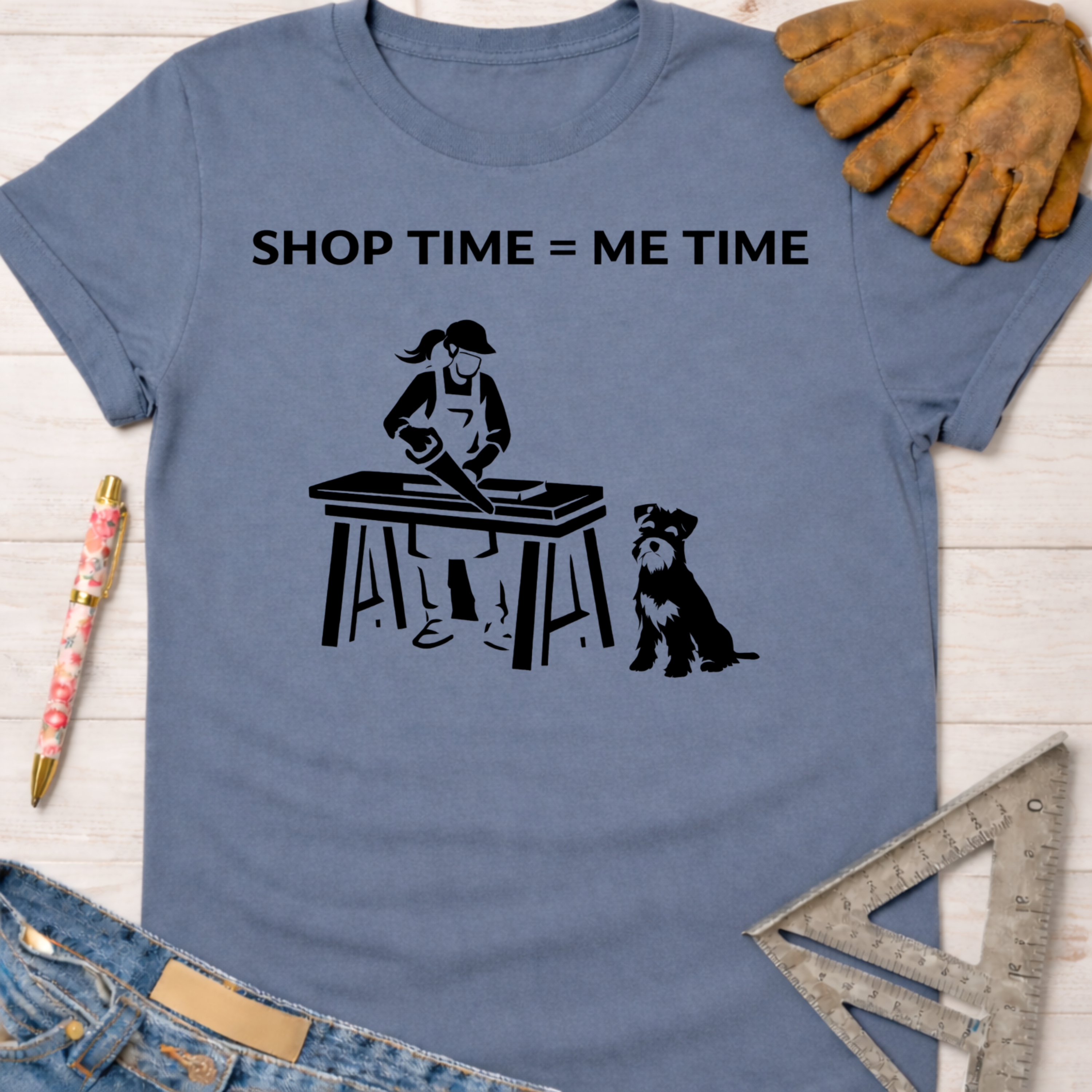 Women's funny woodworking graphic tee shirt for female woodworkers, makers, and DIY builders — Sawdust & Ponytails. Blue cotton tee with "SHOP TIME = ME TIME" text and a graphic of a woman sawing wood with her dog.
