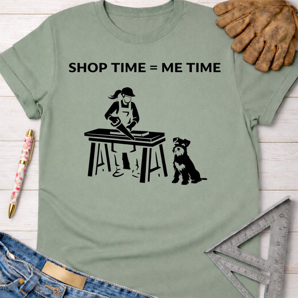 Women's funny woodworking graphic tee shirt for female woodworkers, makers, and DIY builders — Sawdust & Ponytails. Sage green cotton tee with "SHOP TIME = ME TIME" text and a graphic of a woman sawing wood with a dog.