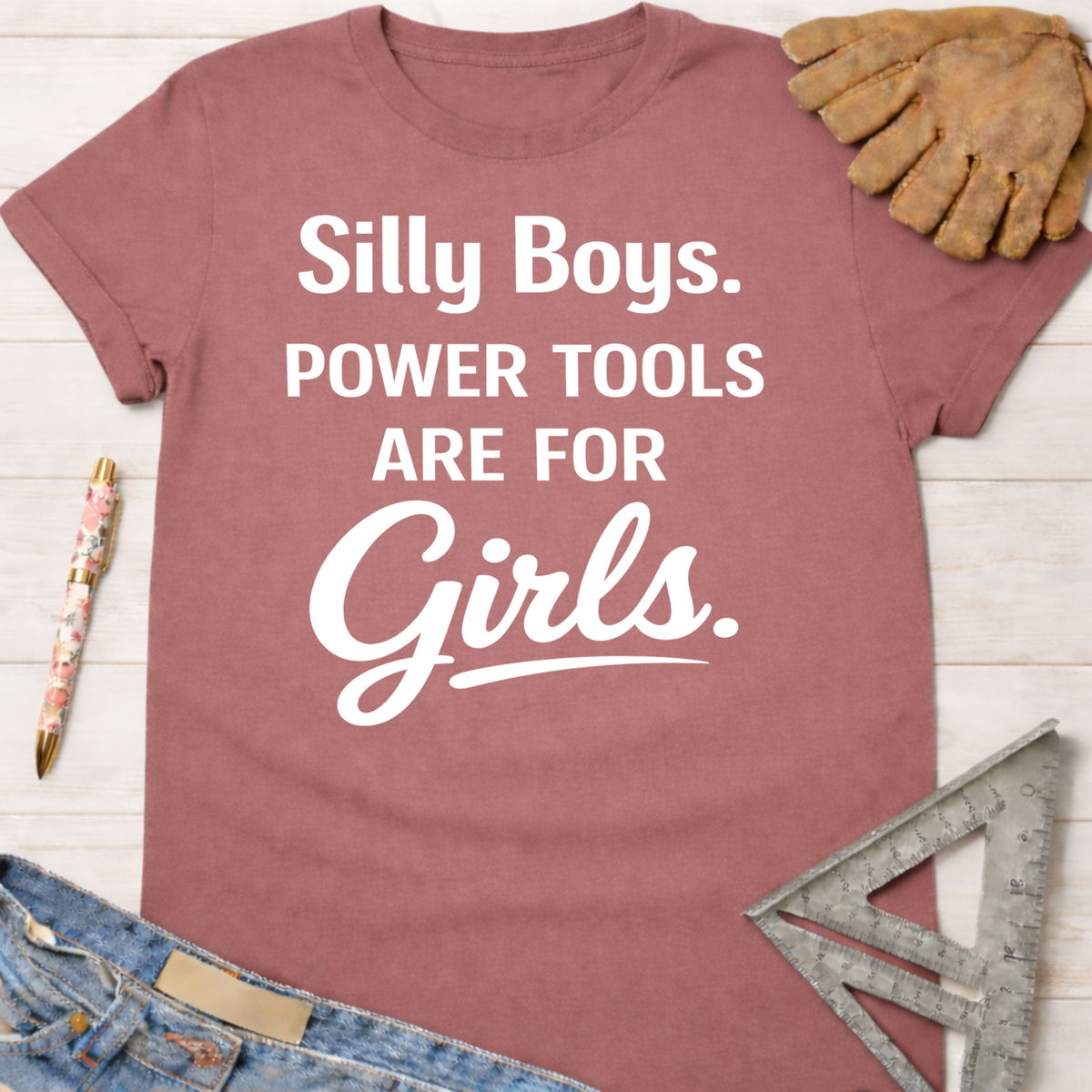 Women's funny woodworking graphic tee shirt for female woodworkers, makers, and DIY builders — Sawdust & Ponytails. Mauve cotton tee with "Silly Boys. Power Tools Are For Girls." in white text.