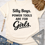 Women's funny woodworking graphic tee shirt for female woodworkers, makers, and DIY builders — Sawdust & Ponytails. Cream t-shirt with "Silly Boys. Power Tools Are For Girls." in black text.