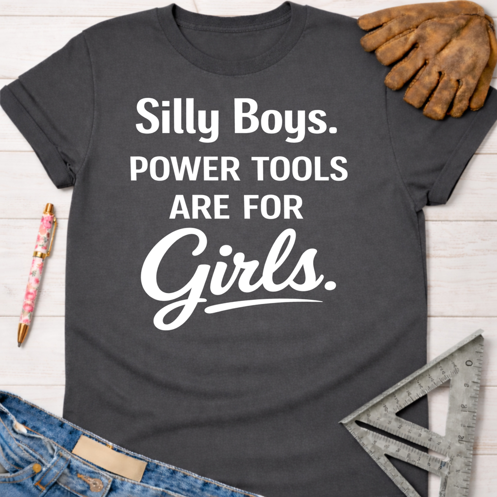 Women's funny woodworking graphic tee shirt for female woodworkers, makers, and DIY builders — Sawdust & Ponytails. Dark gray cotton tee with "Silly Boys. Power Tools Are For Girls." in white text.