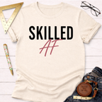 Cream cotton "SKILLED AF" t-shirt with black and pink text, styled with jeans and tools.