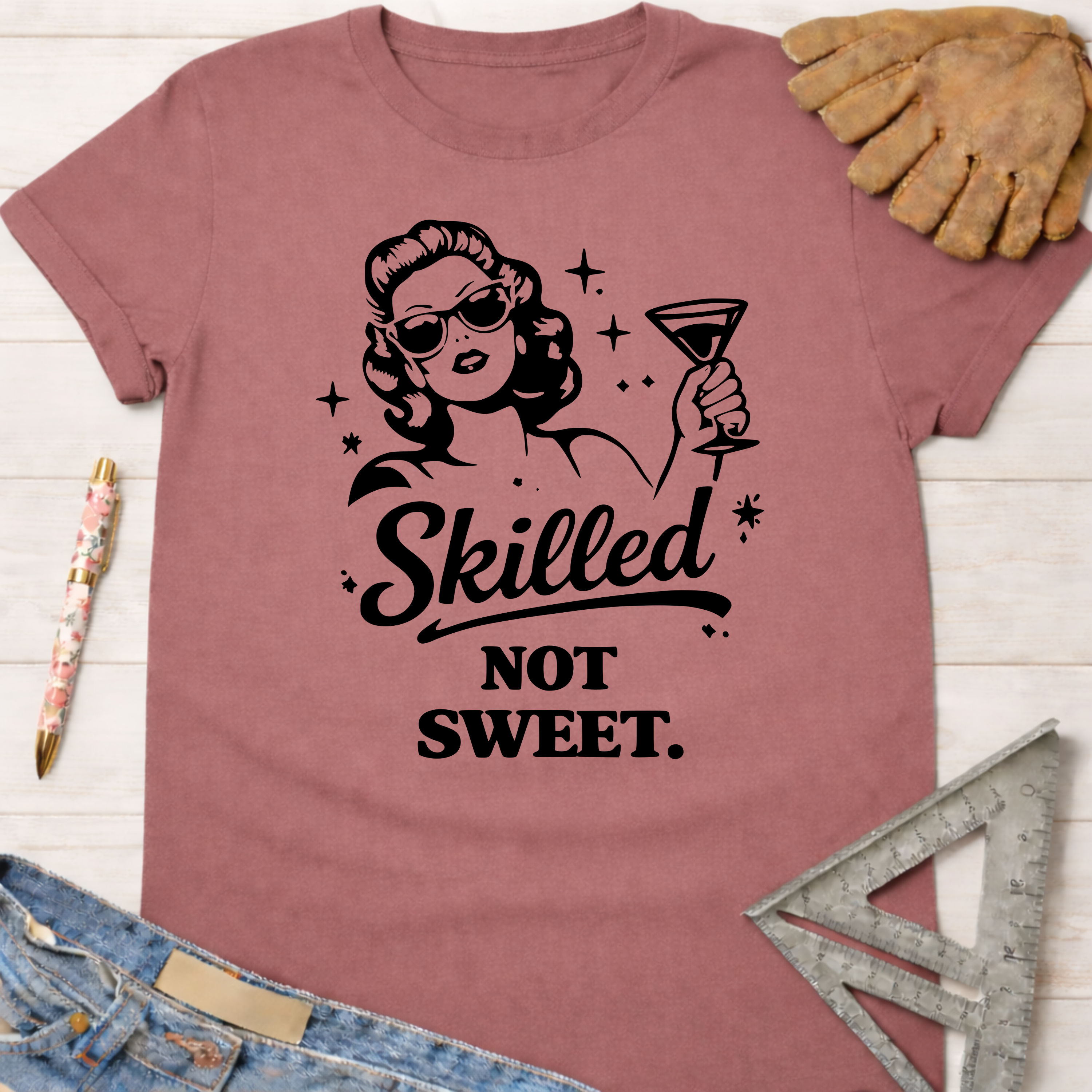 Women's funny woodworking graphic tee shirt for female woodworkers, makers, and DIY builders — Sawdust & Ponytails. Mauve t-shirt with "Skilled Not Sweet" text and a retro woman holding a martini.