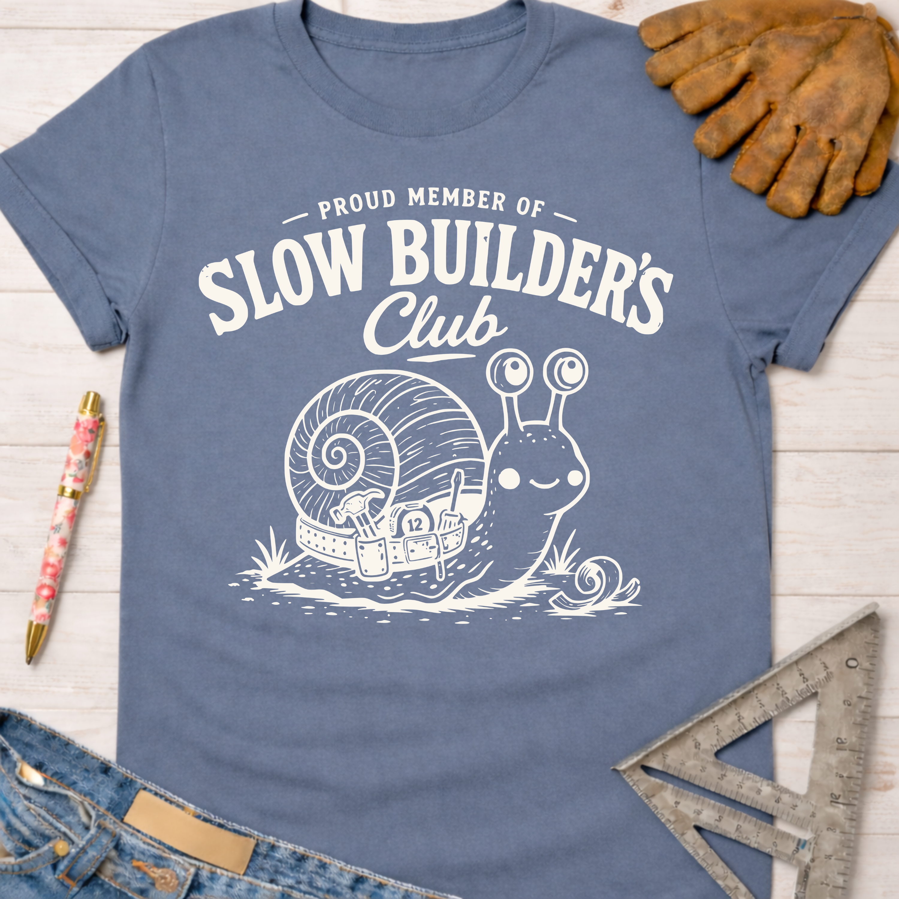 Women's funny woodworking graphic tee shirt for female woodworkers, makers, and DIY builders — Sawdust & Ponytails. Blue tee with "Slow Builder's Club" snail graphic.