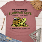 Women's funny woodworking graphic tee shirt for female woodworkers, makers, and DIY builders — Sawdust & Ponytails. Mauve cotton tee with "Proud Member of the Slow Builder's Club" text and a turtle carrying tools.