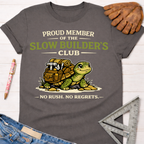 Women's funny woodworking graphic tee shirt for female woodworkers, makers, and DIY builders — Sawdust & Ponytails. Charcoal cotton tee with "Proud Member of the Slow Builder's Club" text and a turtle carrying tools.