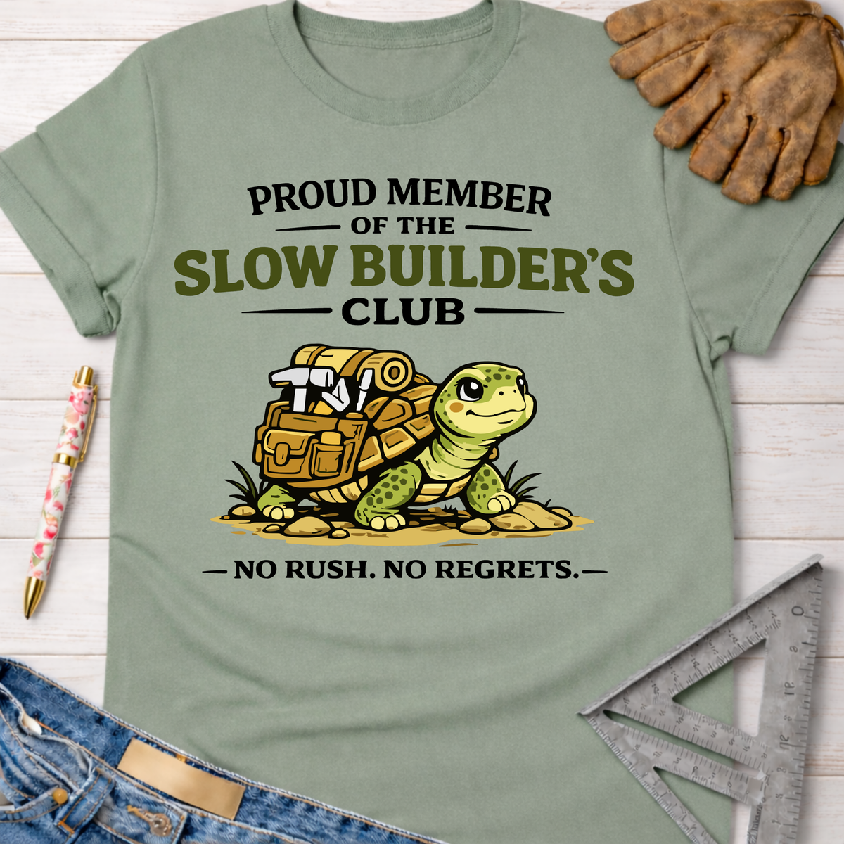 Women's funny woodworking graphic tee shirt for female woodworkers, makers, and DIY builders — Sawdust & Ponytails. Sage green cotton tee with "Slow Builder's Club" turtle graphic.