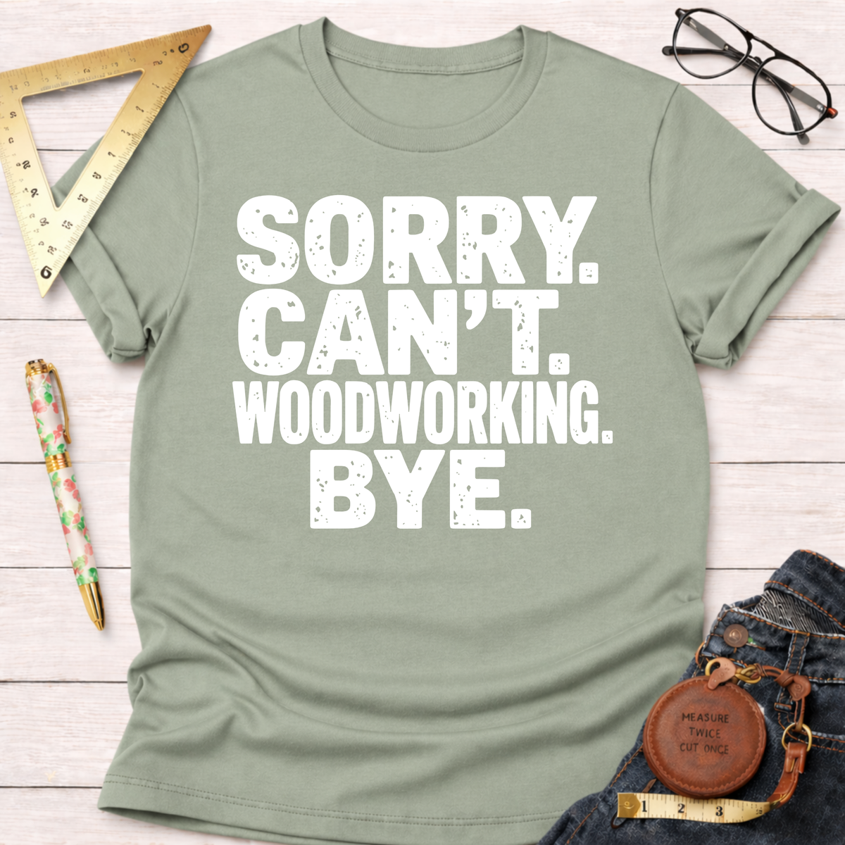 Women's funny woodworking graphic tee shirt for female woodworkers, makers, and DIY builders — Sawdust & Ponytails. Sage green short-sleeve tee with "SORRY. CAN'T. WOODWORKING. BYE." in white distressed text.