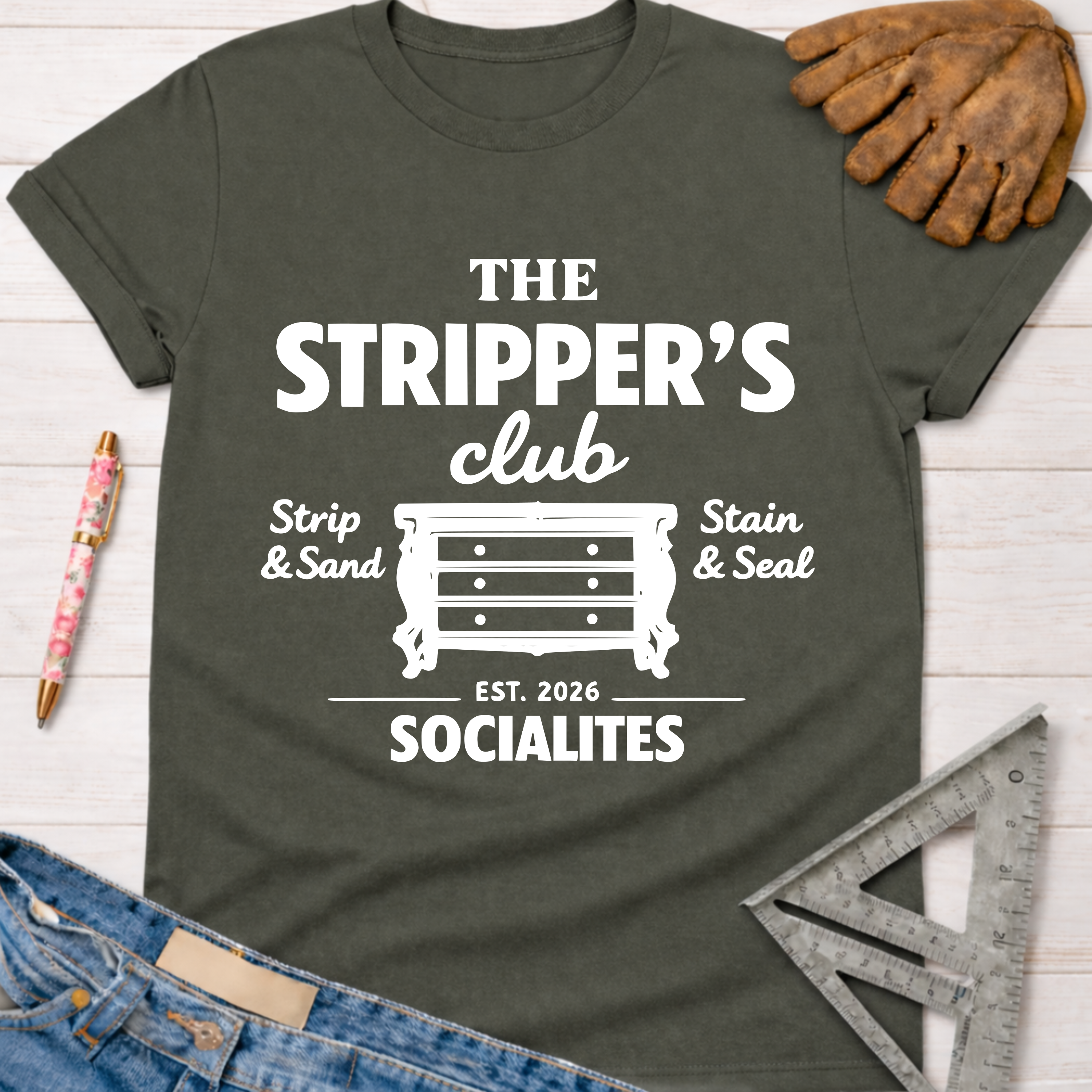 Women's funny woodworking graphic tee shirt for female woodworkers, makers, and DIY builders — Sawdust & Ponytails. Dark gray tee with white "The Stripper's Club Socialites" graphic featuring a dresser, "Strip & Sand," and "Stain & Seal.
