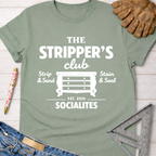 Women's funny woodworking graphic tee shirt for female woodworkers, makers, and DIY builders — Sawdust & Ponytails. Sage green t-shirt with "The Stripper's Club Socialites" graphic featuring a dresser.