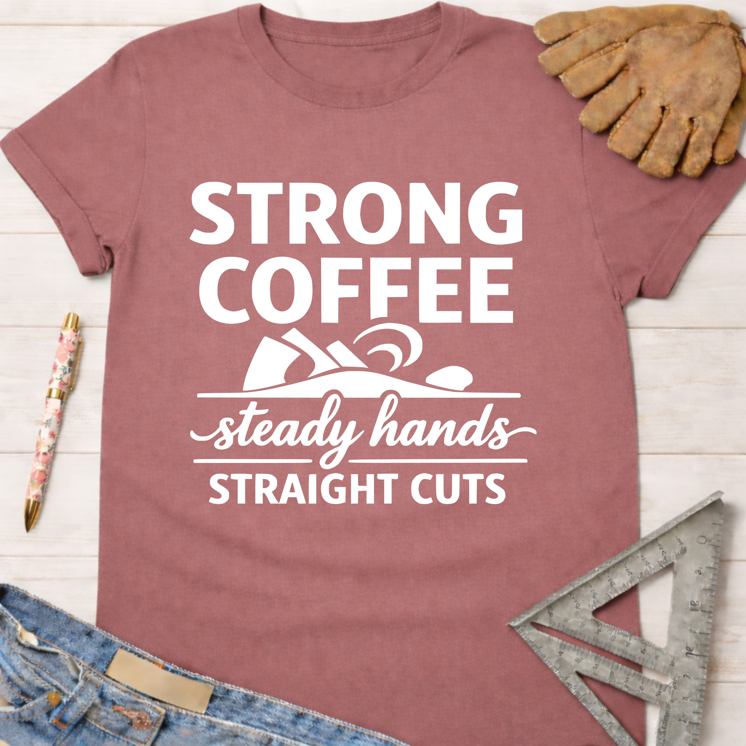 Women's funny woodworking graphic tee shirt for female woodworkers, makers, and DIY builders — Sawdust & Ponytails. Mauve t-shirt with "Strong Coffee Steady Hands Straight Cuts" graphic.
