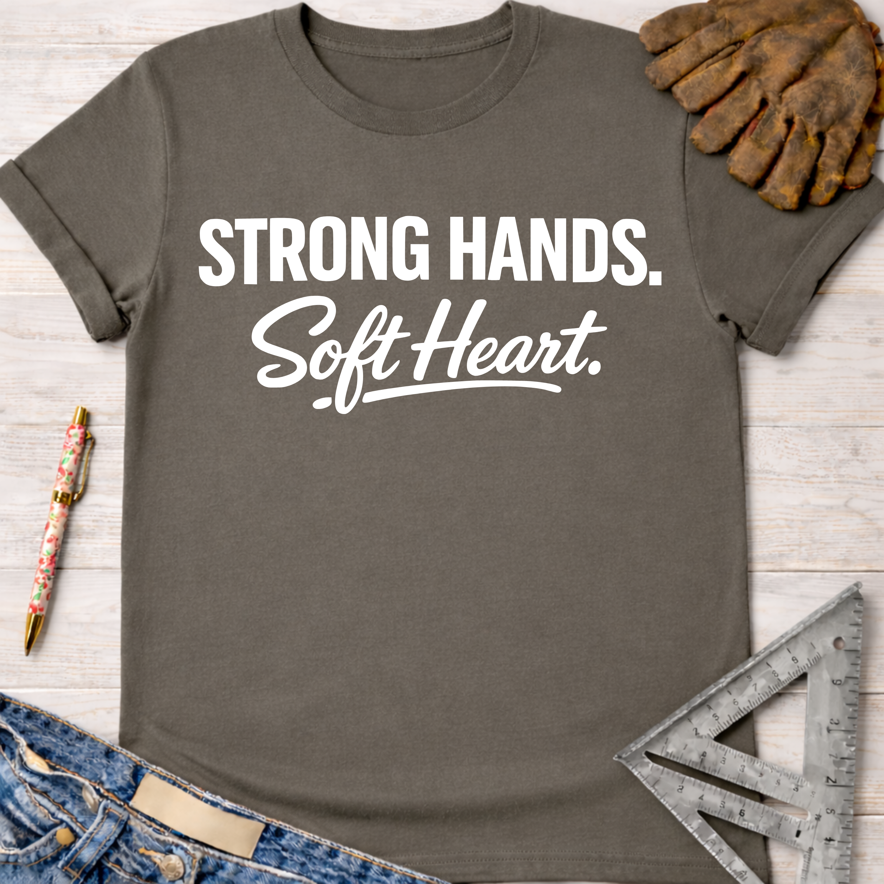 Women's funny woodworking graphic tee shirt for female woodworkers, makers, and DIY builders — Sawdust & Ponytails. Dark gray t-shirt with "Strong Hands. Soft Heart." in white text.