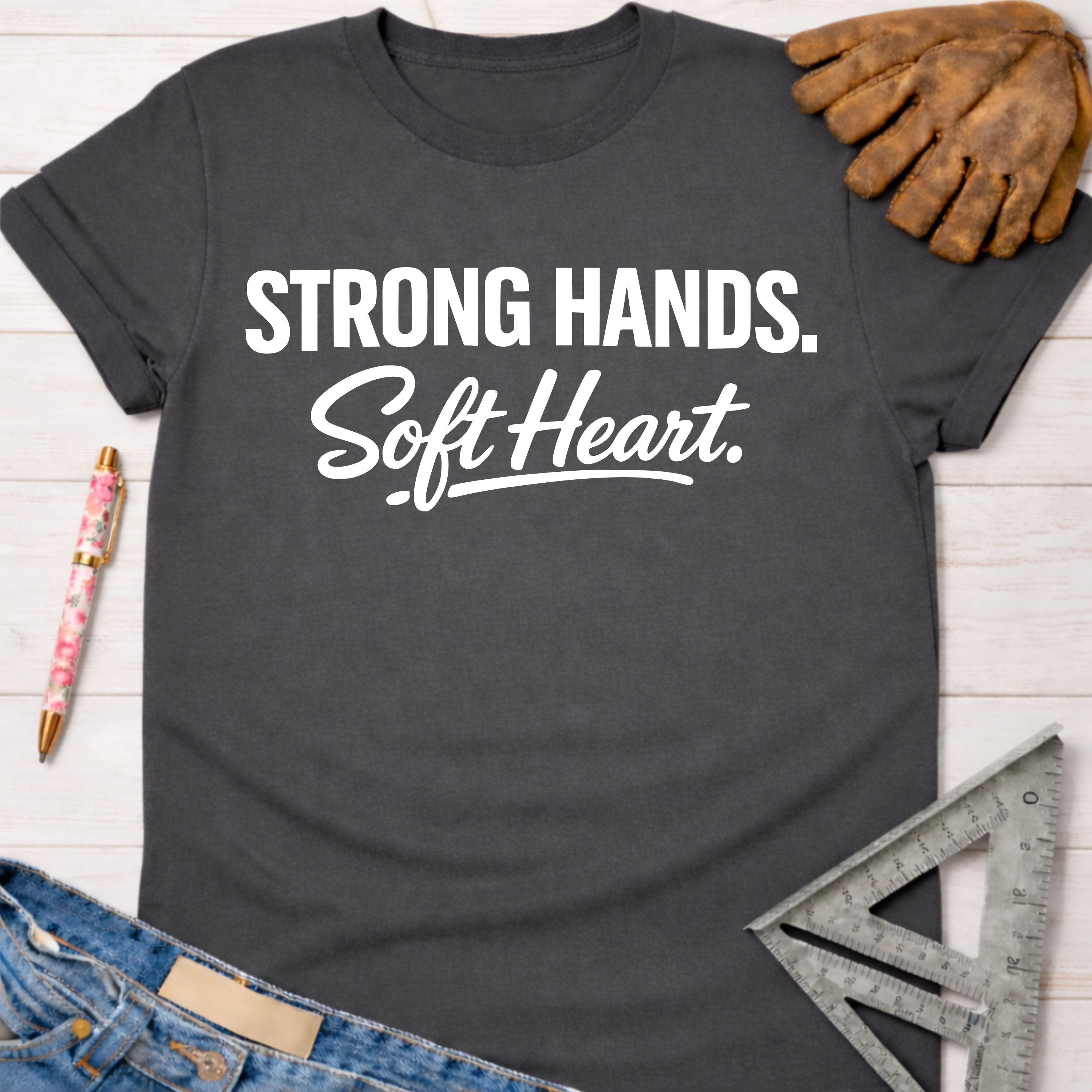 Women's funny woodworking graphic tee shirt for female woodworkers, makers, and DIY builders — Sawdust & Ponytails. Dark gray t-shirt with "Strong Hands. Soft Heart." in white text.