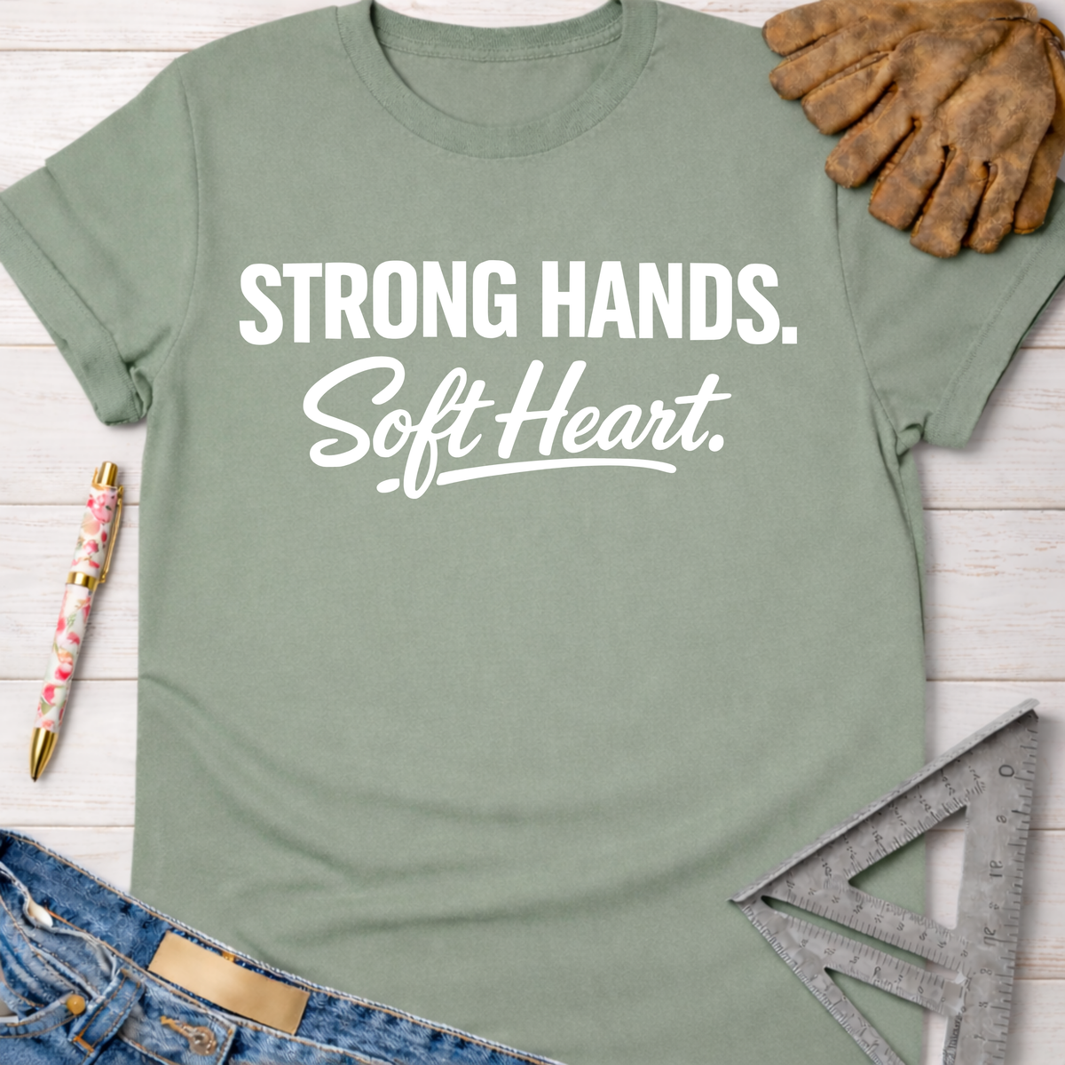 Women's funny woodworking graphic tee shirt for female woodworkers, makers, and DIY builders — Sawdust & Ponytails. Sage green cotton tee with "Strong Hands. Soft Heart." in white text.