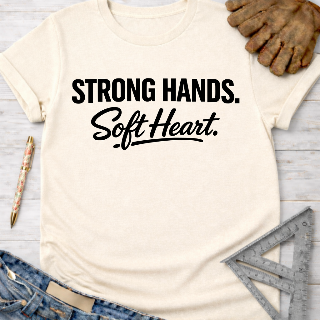 Women's funny woodworking graphic tee shirt for female woodworkers, makers, and DIY builders — Sawdust & Ponytails. Cream cotton tee with "Strong Hands. Soft Heart." in black text.