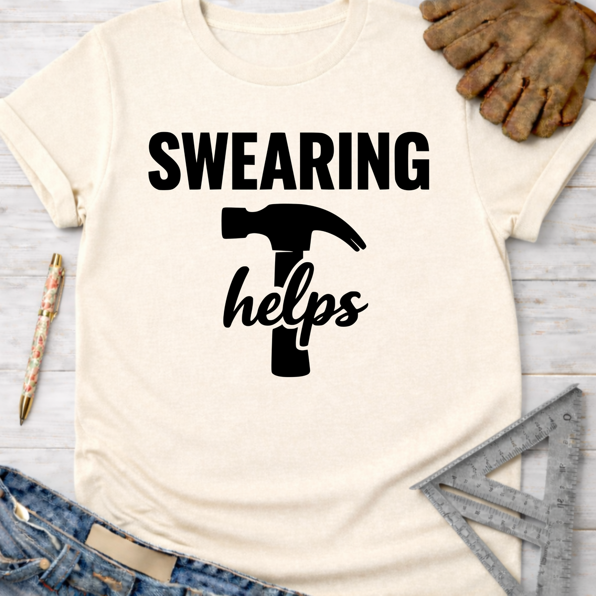 Women's funny woodworking graphic tee shirt for female woodworkers, makers, and DIY builders — Sawdust & Ponytails. Cream t-shirt with "SWEARING helps" and hammer graphic.