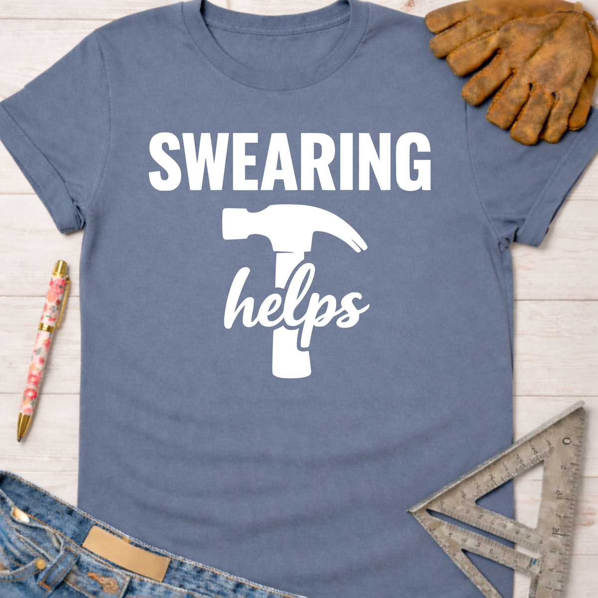 Women's funny woodworking graphic tee shirt for female woodworkers, makers, and DIY builders — Sawdust & Ponytails. Blue cotton tee with "SWEARING helps" text and hammer graphic.