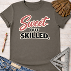Women's funny woodworking graphic tee shirt for female woodworkers, makers, and DIY builders — Sawdust & Ponytails. Dark gray cotton tee with "Sweet But Skilled" in red and black text.