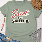 Women's funny woodworking graphic tee shirt for female woodworkers, makers, and DIY builders — Sawdust & Ponytails. Sage green cotton tee with "Sweet But Skilled" text.