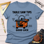 Women's funny woodworking graphic tee shirt for female woodworkers, makers, and DIY builders — Sawdust & Ponytails. Light blue cotton tee with an orange table saw diagram and humorous safety tips.