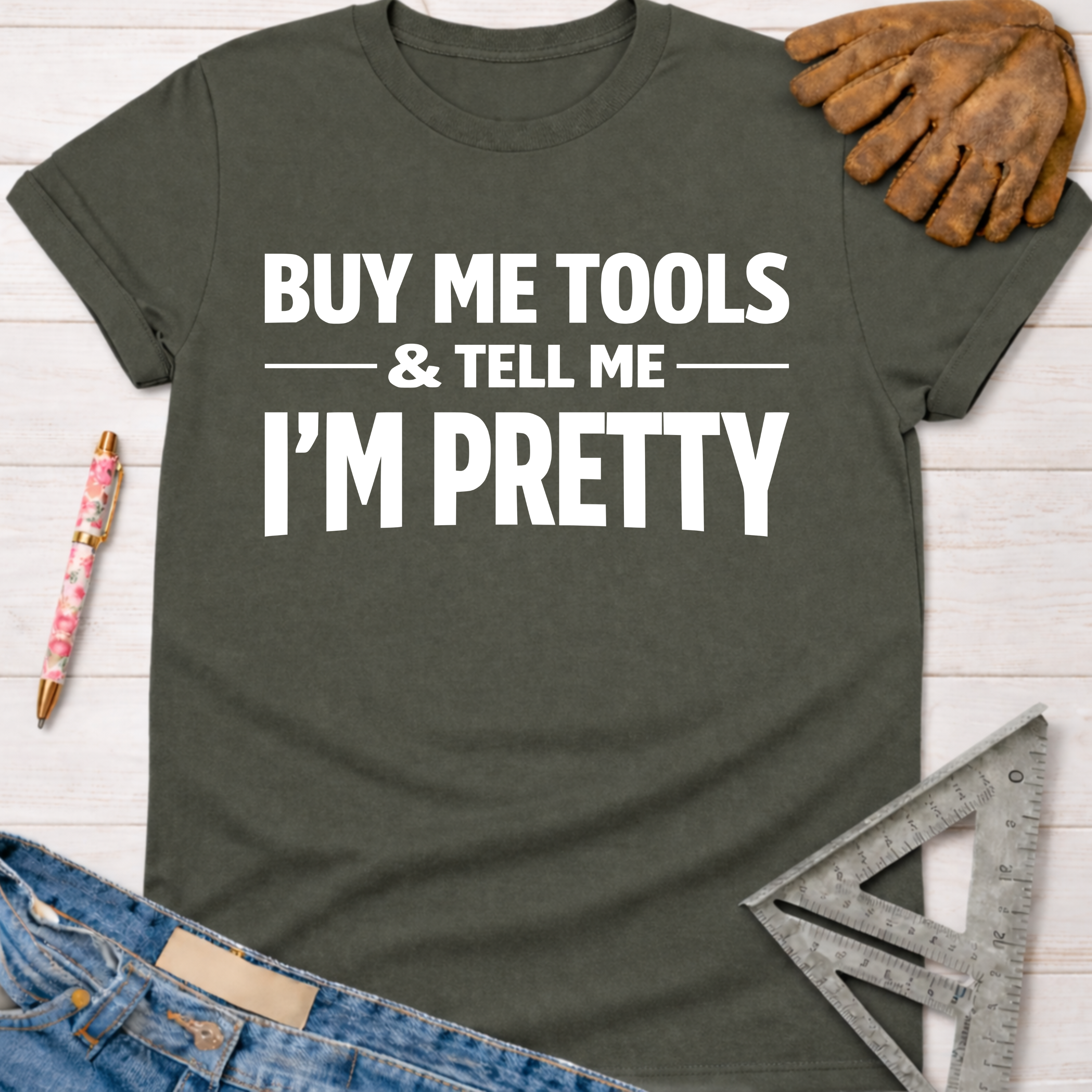 Women's funny woodworking graphic tee shirt for female woodworkers, makers, and DIY builders — Sawdust & Ponytails. Dark gray cotton t-shirt with "BUY ME TOOLS & TELL ME I'M PRETTY" in white text.