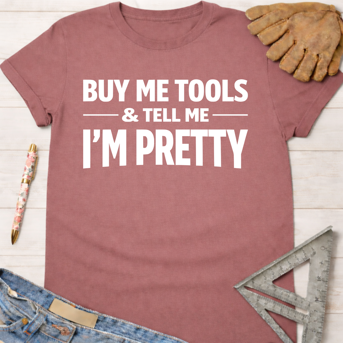 Women's funny woodworking graphic tee shirt for female woodworkers, makers, and DIY builders — Sawdust & Ponytails. Mauve cotton tee with "BUY ME TOOLS & TELL ME I'M PRETTY" in white text.