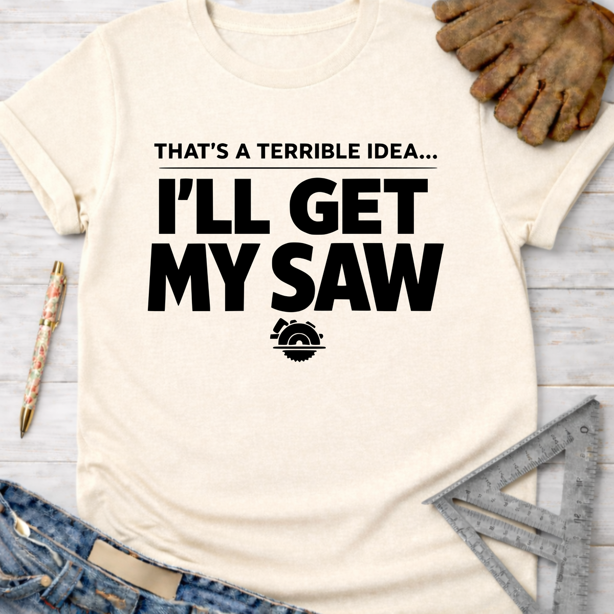 Women's funny woodworking graphic tee shirt for female woodworkers, makers, and DIY builders — Sawdust & Ponytails. Cream t-shirt with "THAT'S A TERRIBLE IDEA... I'LL GET MY SAW" text and saw blade graphic.
