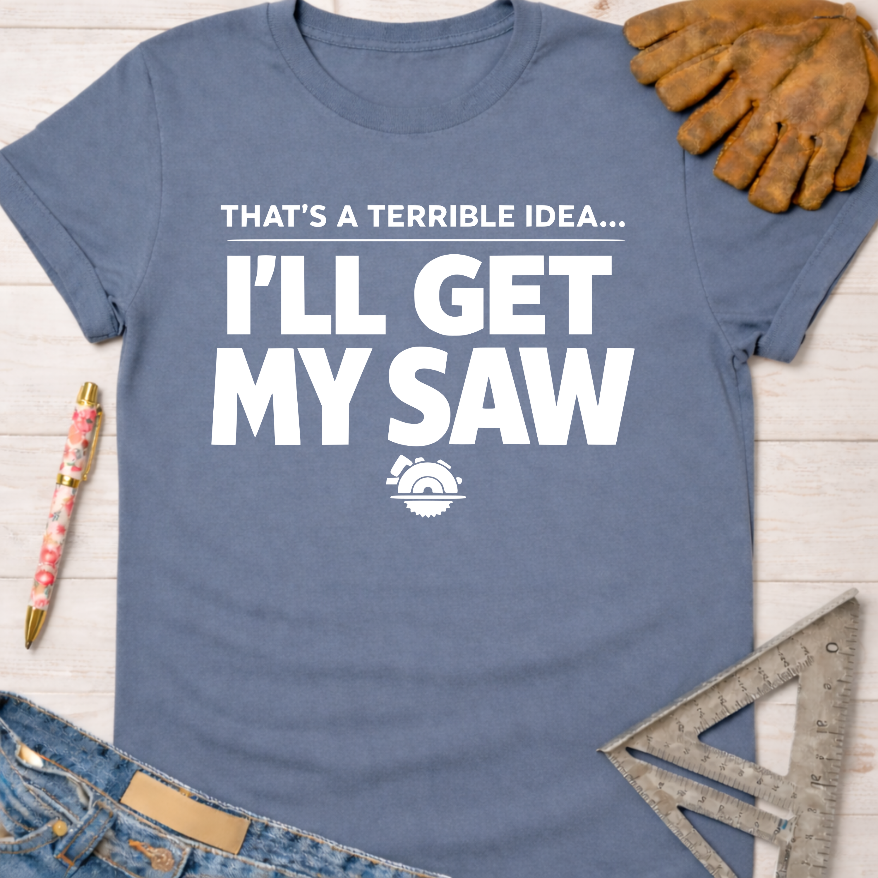 Women's funny woodworking graphic tee shirt for female woodworkers, makers, and DIY builders — Sawdust & Ponytails. Blue cotton t-shirt with "That's A Terrible Idea... I'll Get My Saw" text and saw blade graphic.