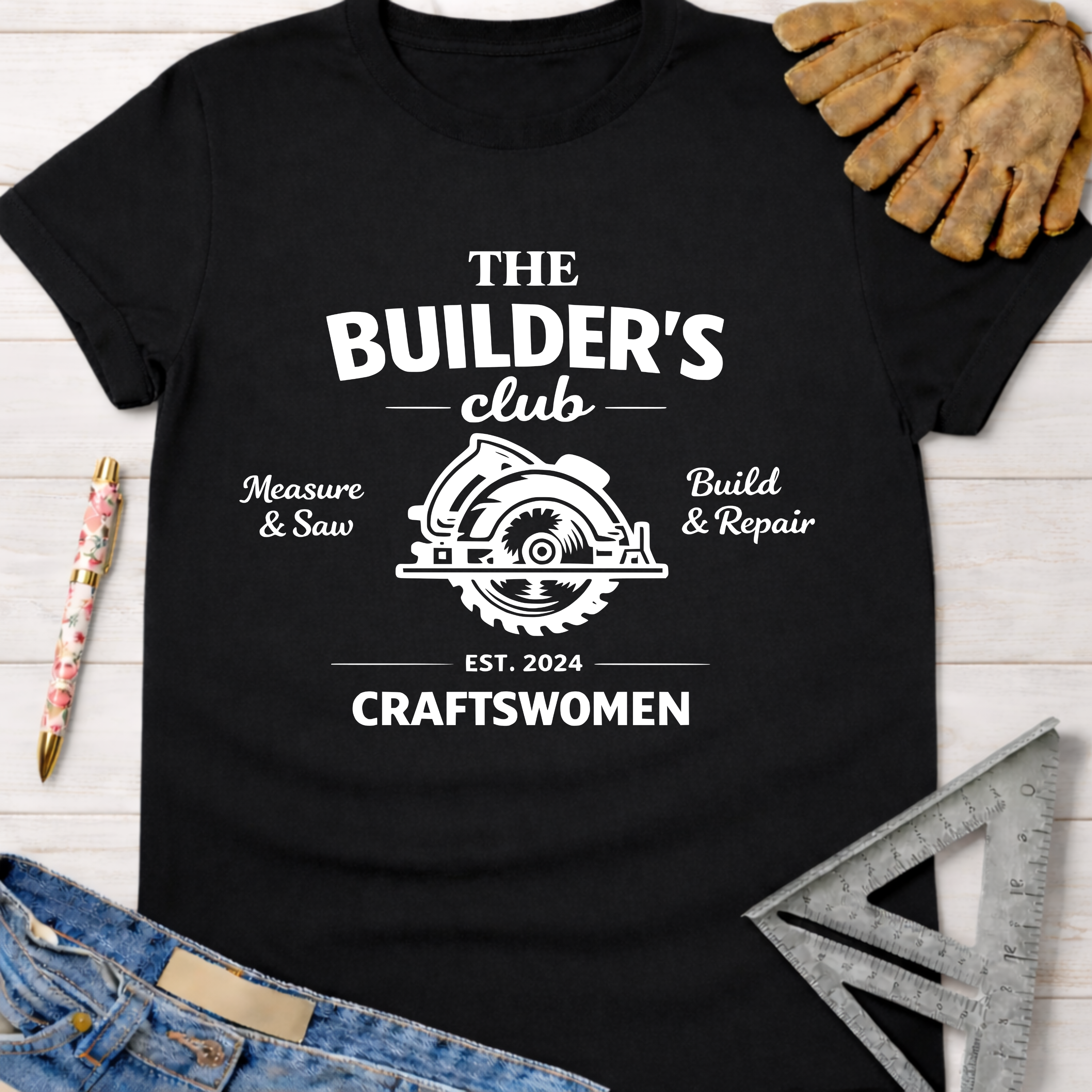 Black cotton "The Builder's Club" graphic tee with circular saw logo, "Craftswomen" text, and work gloves.