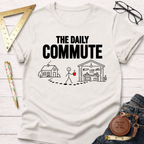 Off-white cotton t-shirt with "THE DAILY COMMUTE" text and a stick figure walking from house to workshop graphic.