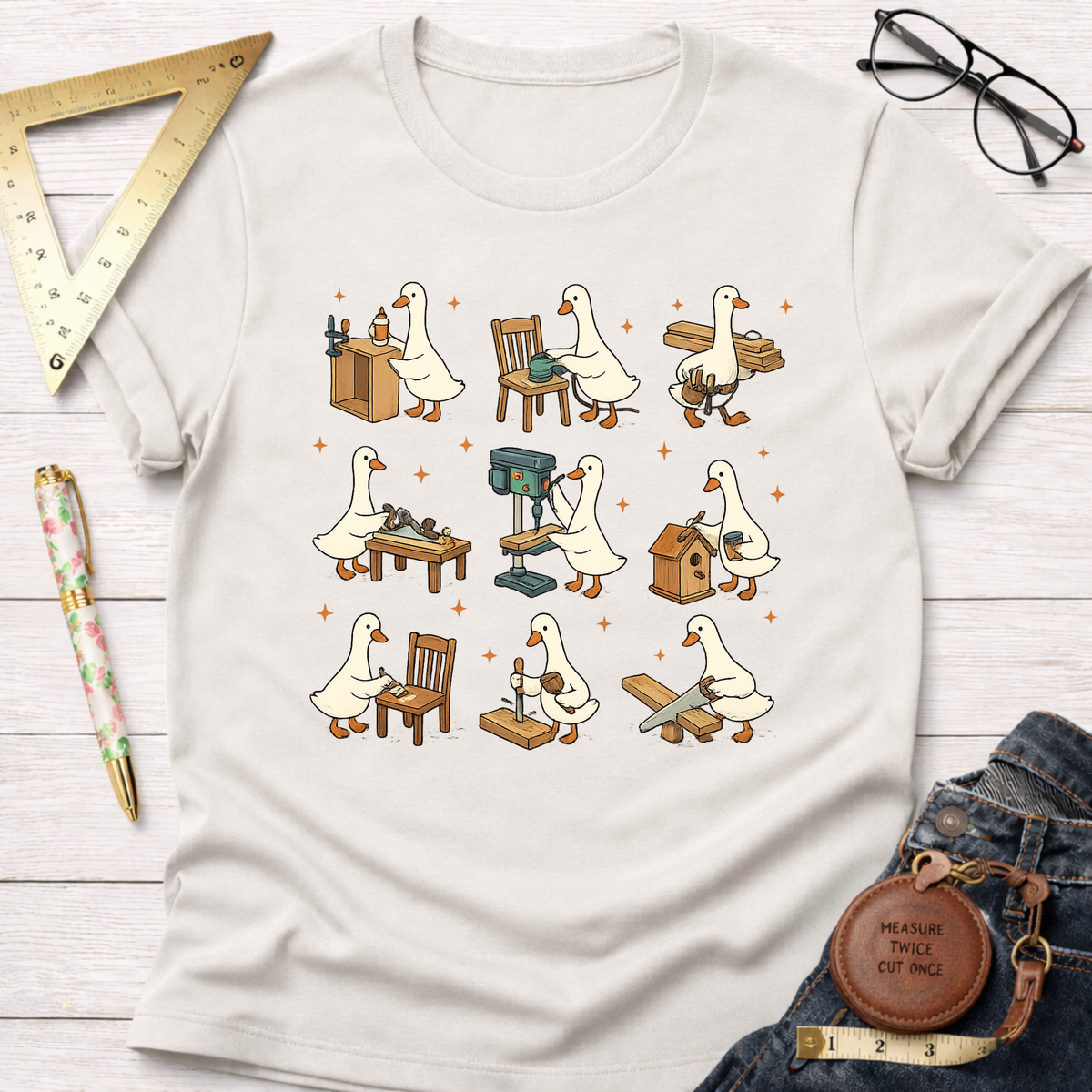 Women's funny woodworking graphic tee shirt for female woodworkers, makers, and DIY builders — Sawdust & Ponytails. Cream t-shirt with cartoon ducks building furniture.