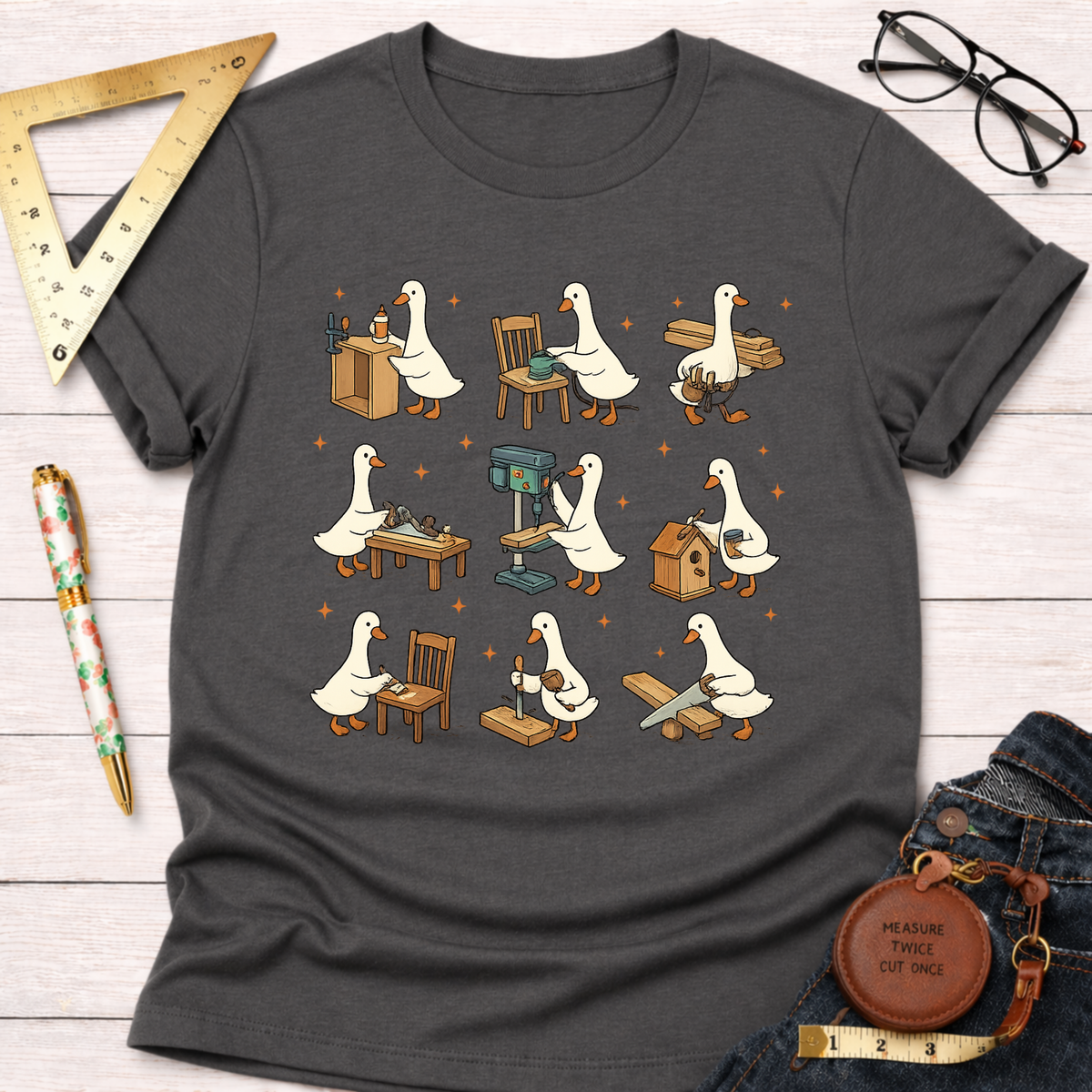 Women's funny woodworking graphic tee shirt for female woodworkers, makers, and DIY builders — Sawdust & Ponytails. Dark gray cotton tee with cartoon ducks building furniture.