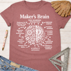 Women's funny woodworking graphic tee shirt for female woodworkers, makers, and DIY builders — Sawdust & Ponytails. Mauve t-shirt with white "Maker's Brain" graphic, half flowers, half brain, surrounded by maker traits.