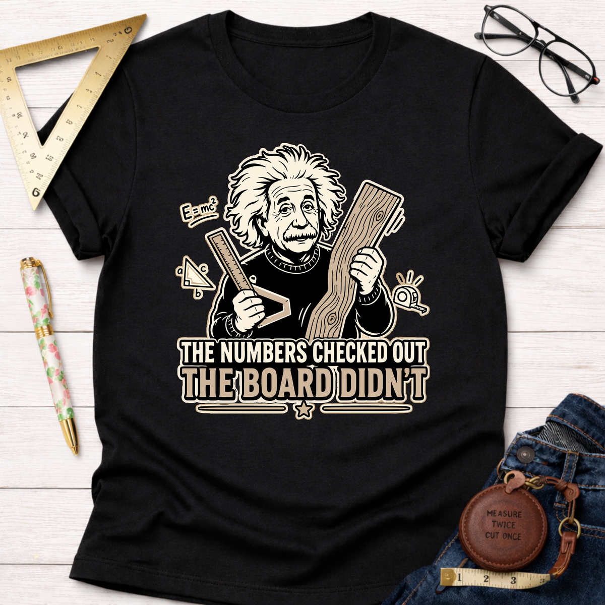 Black cotton t-shirt with a graphic of Albert Einstein holding a ruler and wood, text reads "The Numbers Checked Out The Board Didn't".