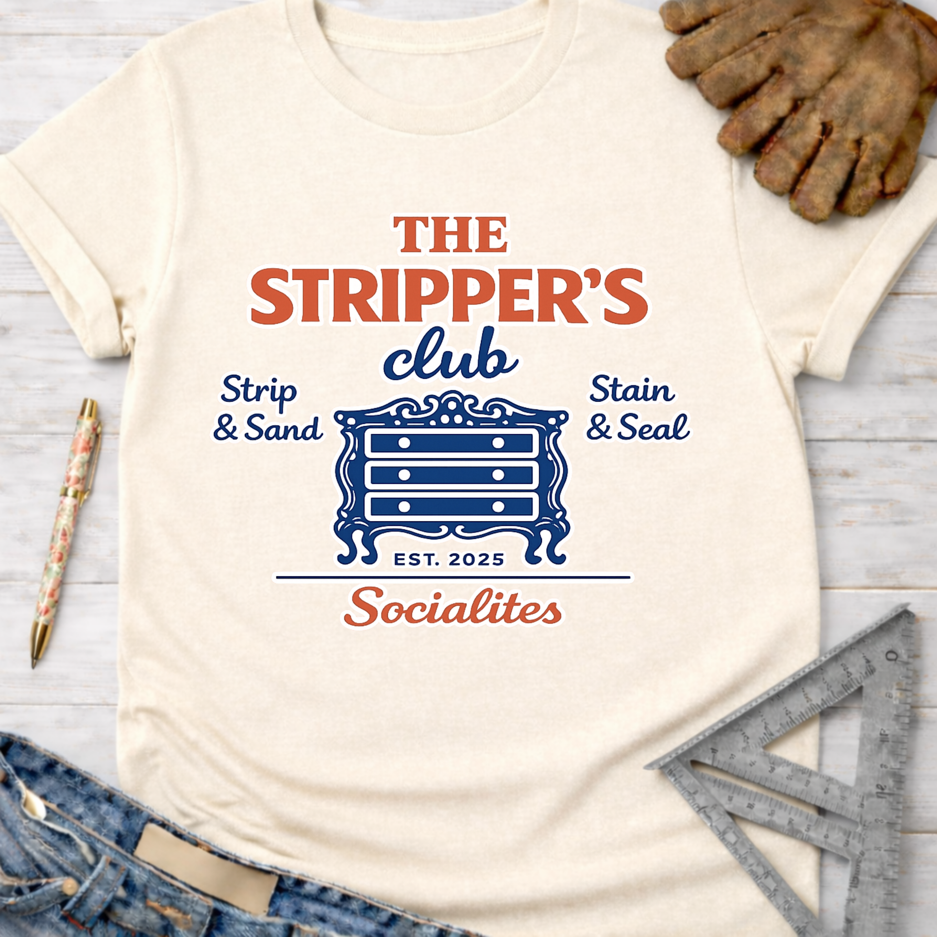 Women's funny woodworking graphic tee shirt for female woodworkers, makers, and DIY builders — Sawdust & Ponytails. Cream t-shirt with "The Stripper's Club Socialites" graphic featuring a dresser.