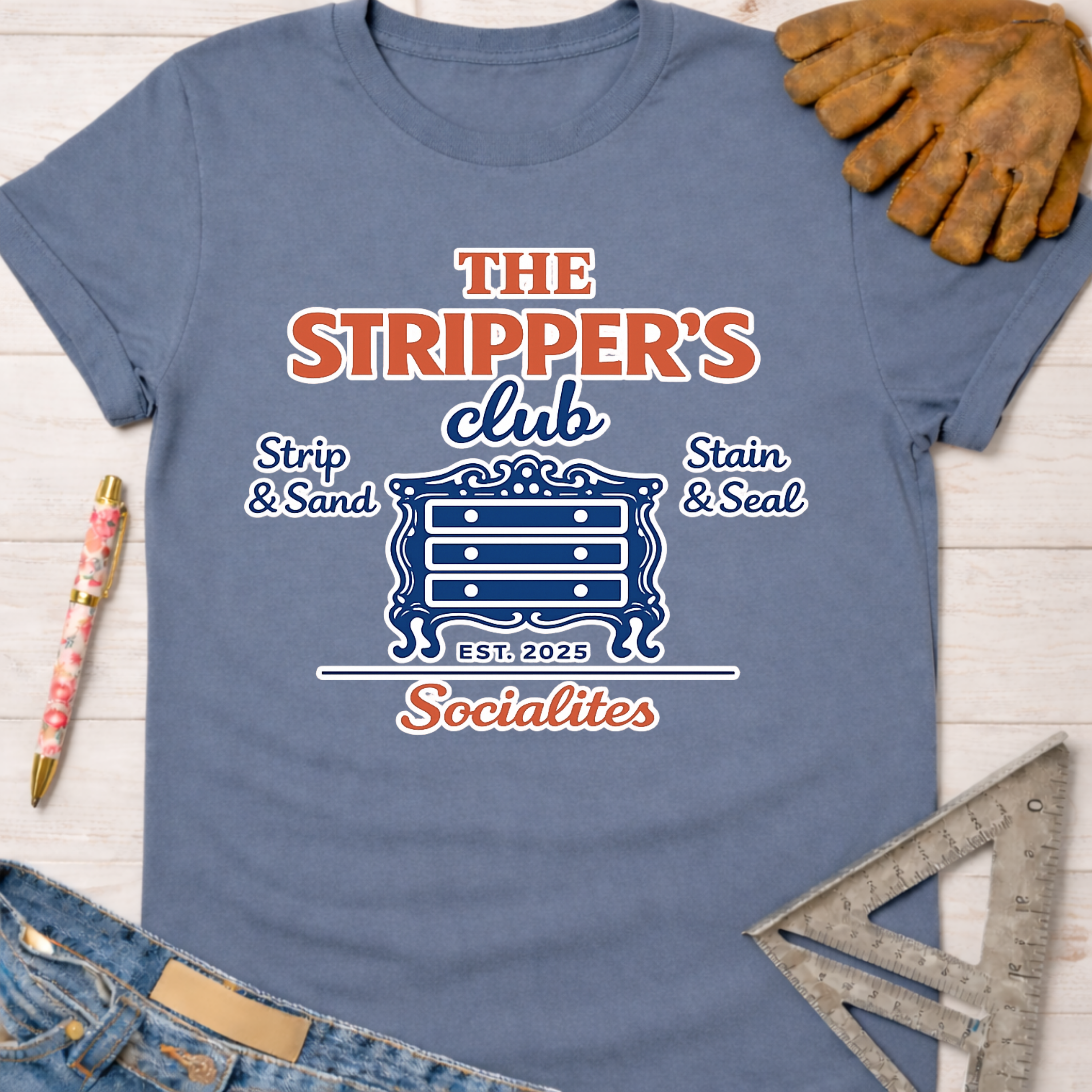 Women's funny woodworking graphic tee shirt for female woodworkers, makers, and DIY builders — Sawdust & Ponytails. Blue cotton tee with "The Stripper's Club Socialites" graphic featuring a dresser, "Strip & Sand," and "Stain & Seal.