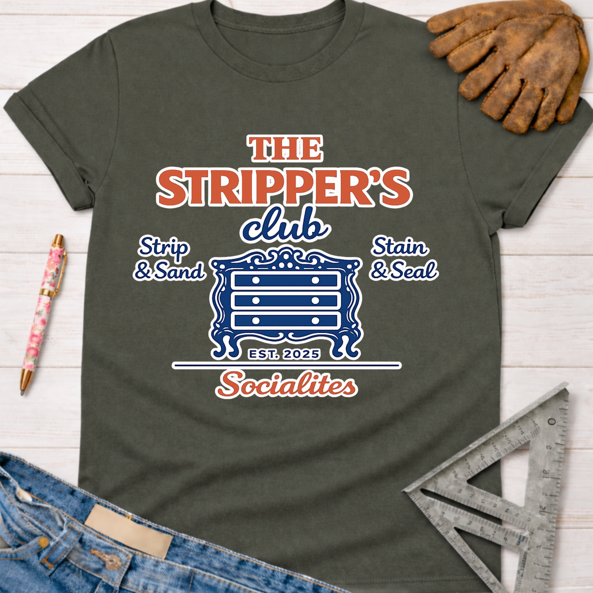 Women's funny woodworking graphic tee shirt for female woodworkers, makers, and DIY builders — Sawdust & Ponytails. Dark gray t-shirt with "The Stripper's Club Socialites" graphic featuring a dresser, "Strip & Sand," and "Stain & Seal.