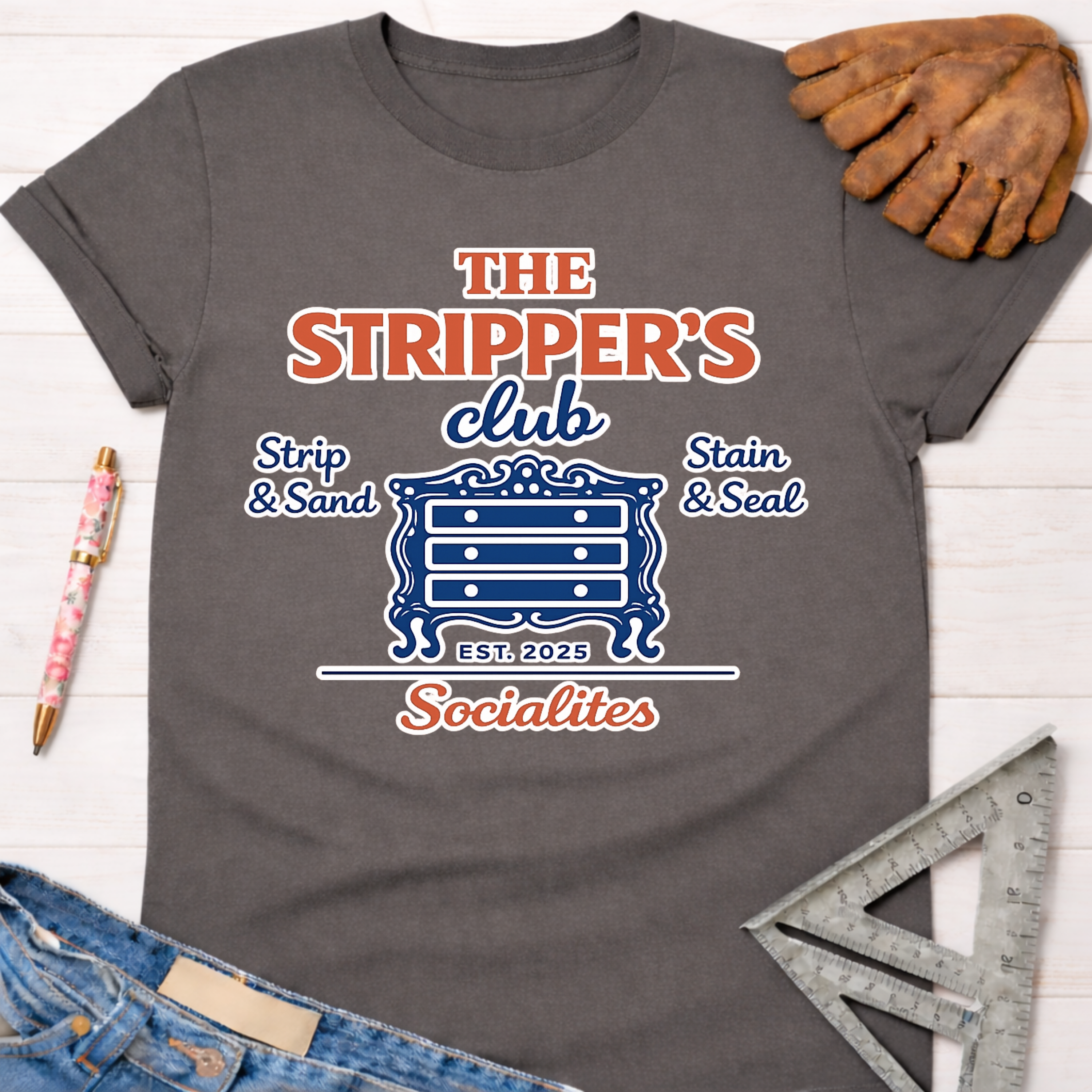 Women's funny woodworking graphic tee shirt for female woodworkers, makers, and DIY builders — Sawdust & Ponytails. Dark gray t-shirt with "The Stripper's Club Socialites" graphic featuring a dresser.