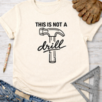 Women's funny woodworking graphic tee shirt for female woodworkers, makers, and DIY builders — Sawdust & Ponytails. Cream short-sleeve tee with "THIS IS NOT A drill" hammer graphic.