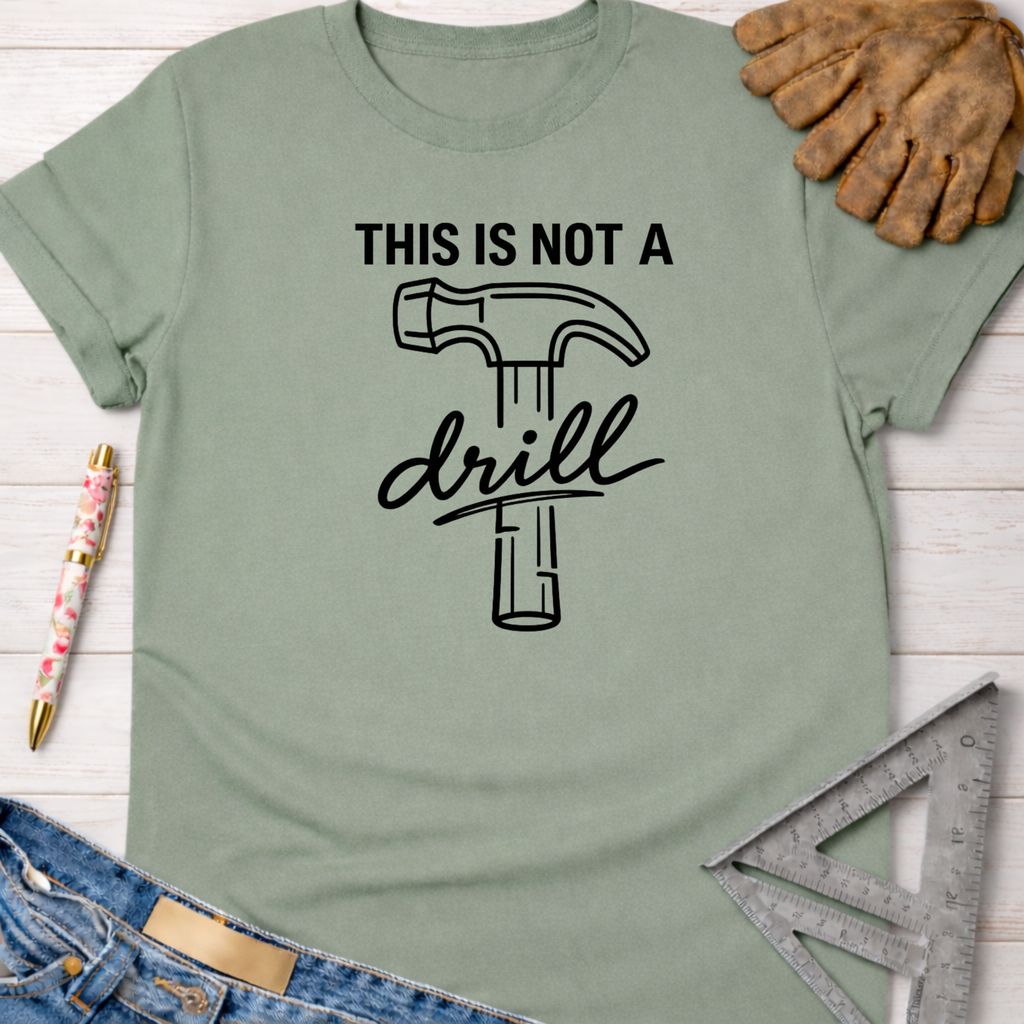 Women's funny woodworking graphic tee shirt for female woodworkers, makers, and DIY builders — Sawdust & Ponytails. Sage green cotton tee with "THIS IS NOT A drill" text and hammer graphic.