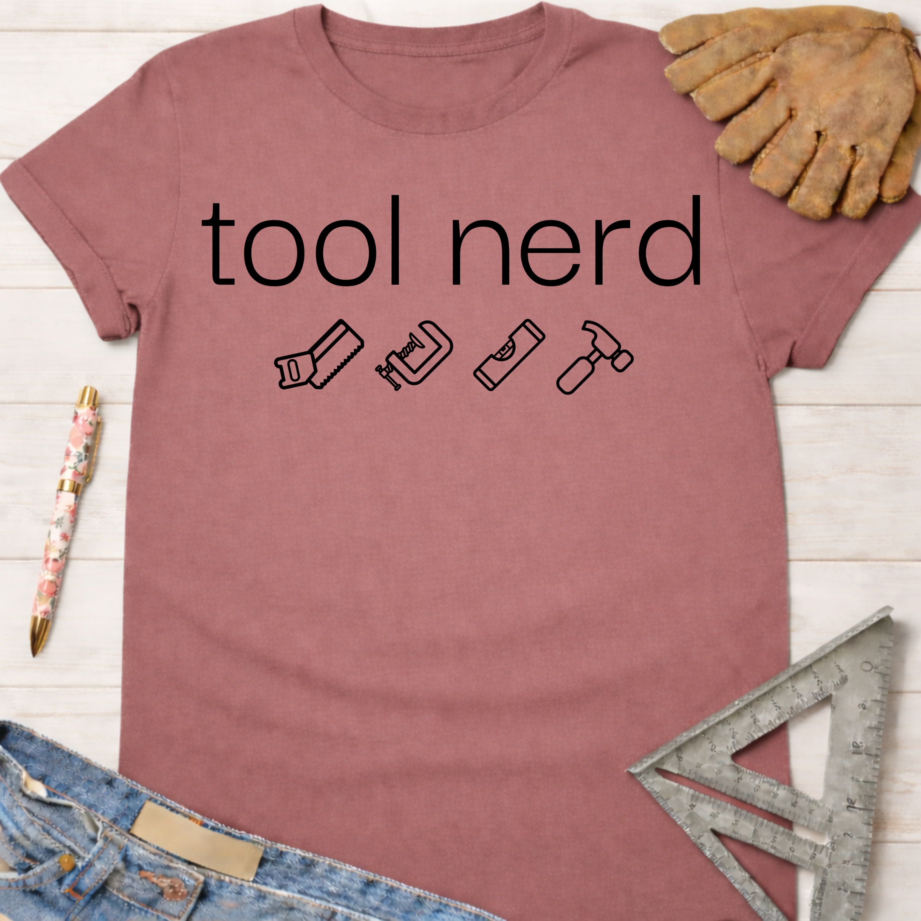 Women's funny woodworking graphic tee shirt for female woodworkers, makers, and DIY builders — Sawdust & Ponytails. Mauve cotton t-shirt with "tool nerd" text and tool icons.