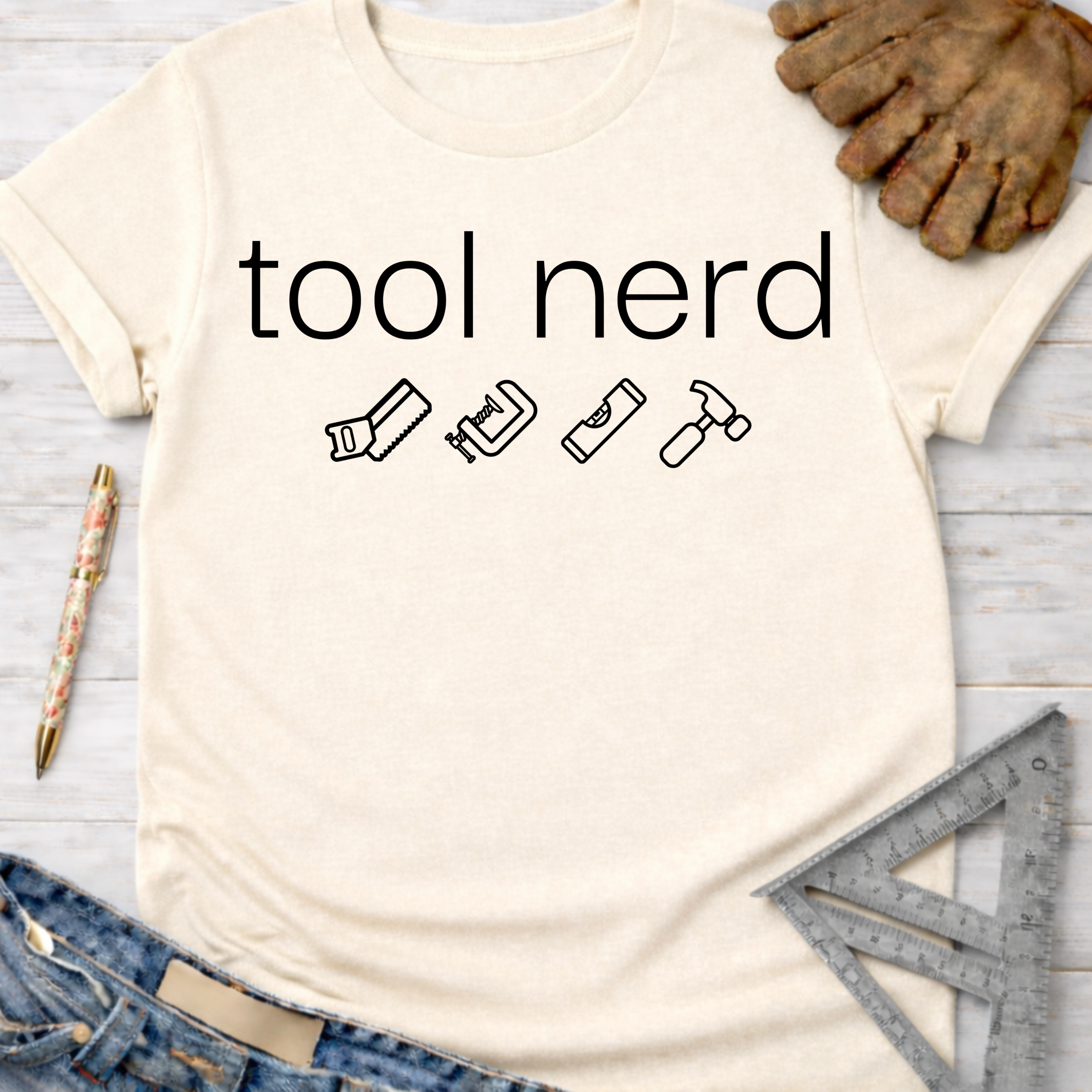 Women's funny woodworking graphic tee shirt for female woodworkers, makers, and DIY builders — Sawdust & Ponytails. Cream t-shirt with "tool nerd" text and tool icons.