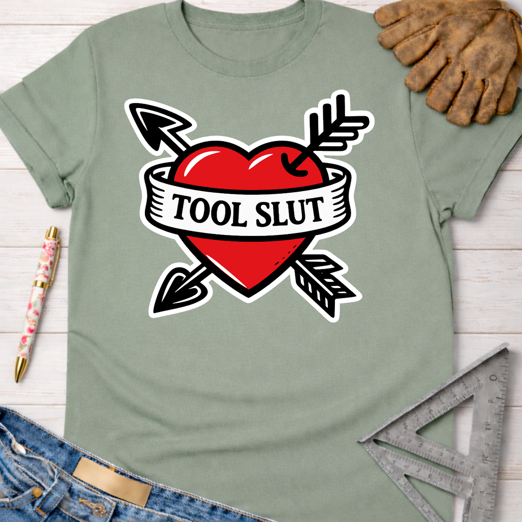 Women's funny woodworking graphic tee shirt for female woodworkers, makers, and DIY builders — Sawdust & Ponytails. Sage green t-shirt with a red heart, black arrows, and "TOOL SLUT" banner.