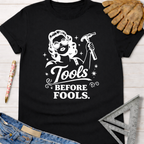 Black "Tools Before Fools" t-shirt with a retro woman holding a hammer. Women's funny woodworking graphic tee shirt for female woodworkers, makers, and DIY builders — Sawdust & Ponytails