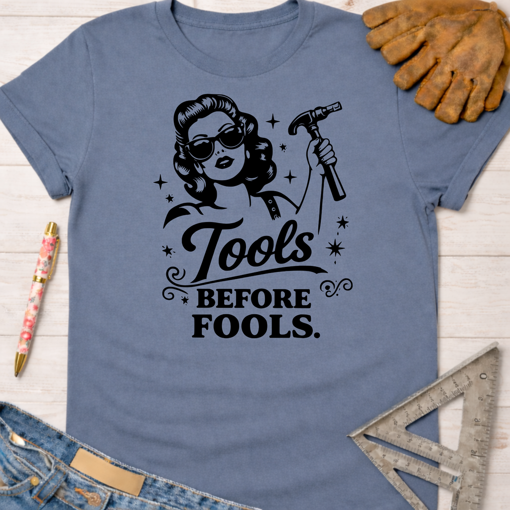 Women's funny woodworking graphic tee shirt for female woodworkers, makers, and DIY builders — Sawdust & Ponytails. Blue cotton tee with "Tools Before Fools" graphic featuring a retro woman holding a hammer.