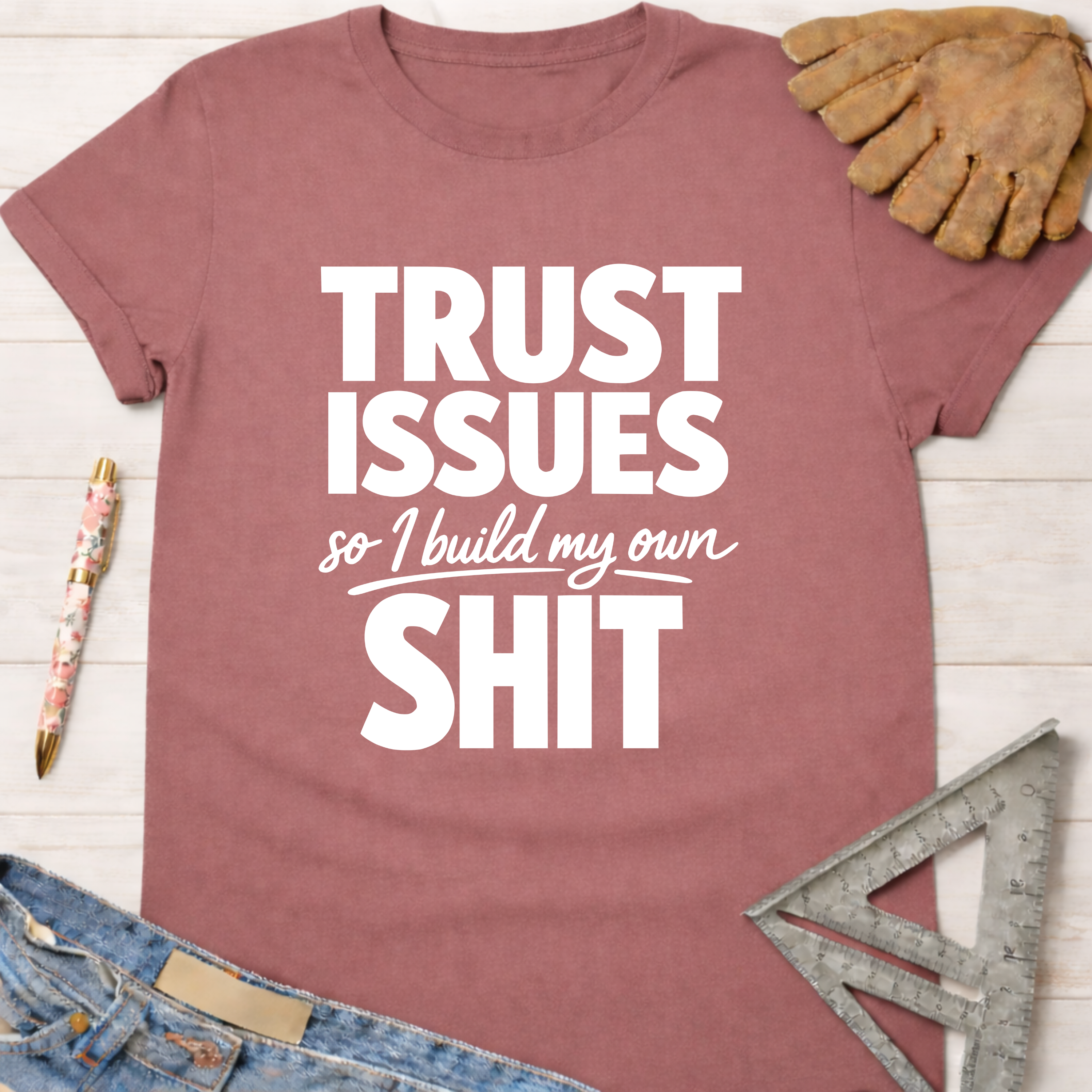 Women's funny woodworking graphic tee shirt for female woodworkers, makers, and DIY builders — Sawdust & Ponytails. Mauve cotton t-shirt with "TRUST ISSUES so I build my own SHIT" in white text.