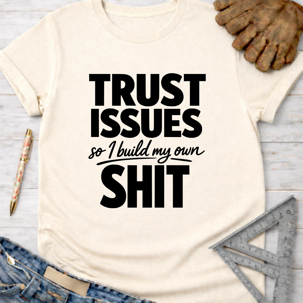 Women's funny woodworking graphic tee shirt for female woodworkers, makers, and DIY builders — Sawdust & Ponytails. Cream t-shirt with "TRUST ISSUES so I build my own SHIT" in black text.