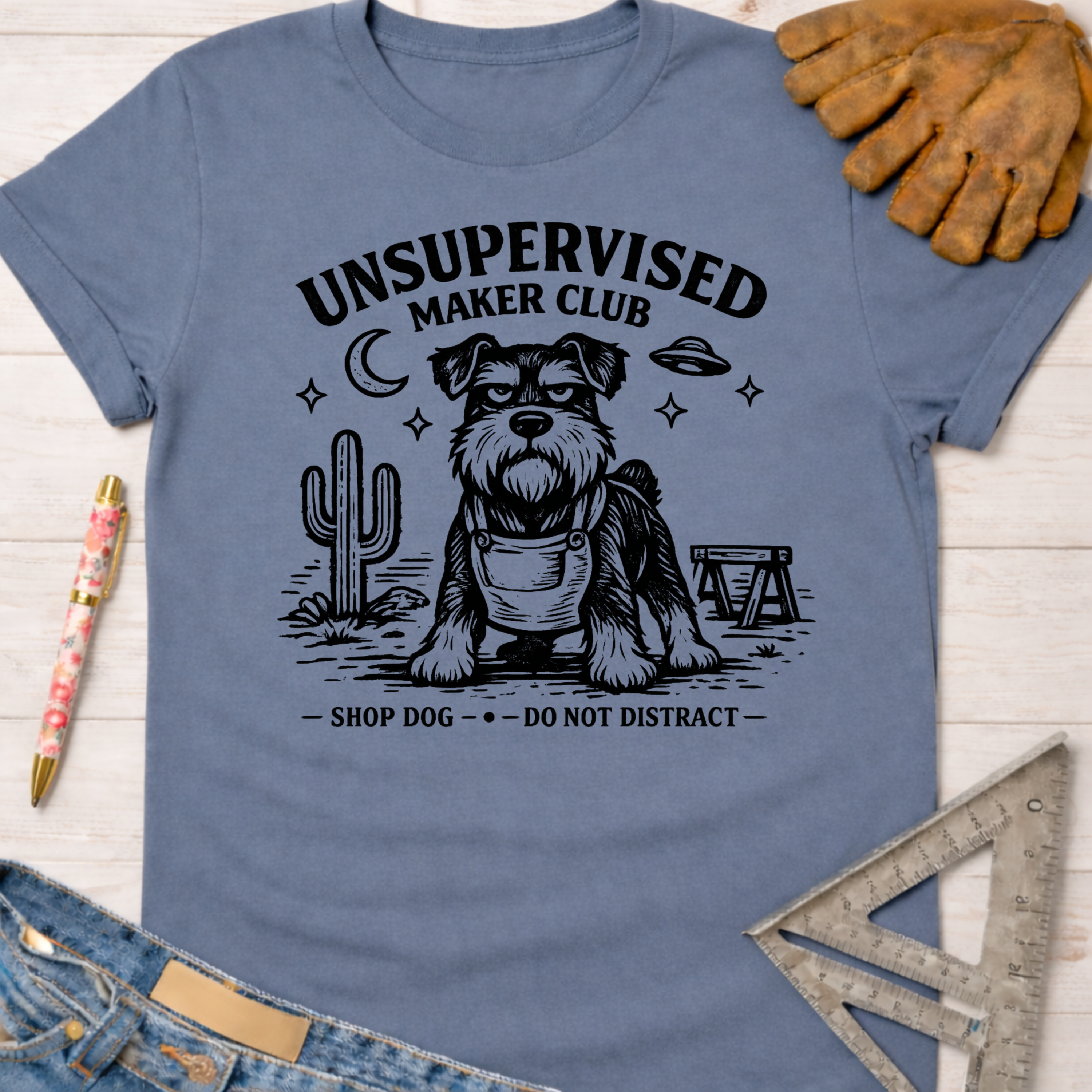 Women's funny woodworking graphic tee shirt for female woodworkers, makers, and DIY builders — Sawdust & Ponytails. Blue cotton tee with "Unsupervised Maker Club" graphic featuring a serious Schnauzer dog.